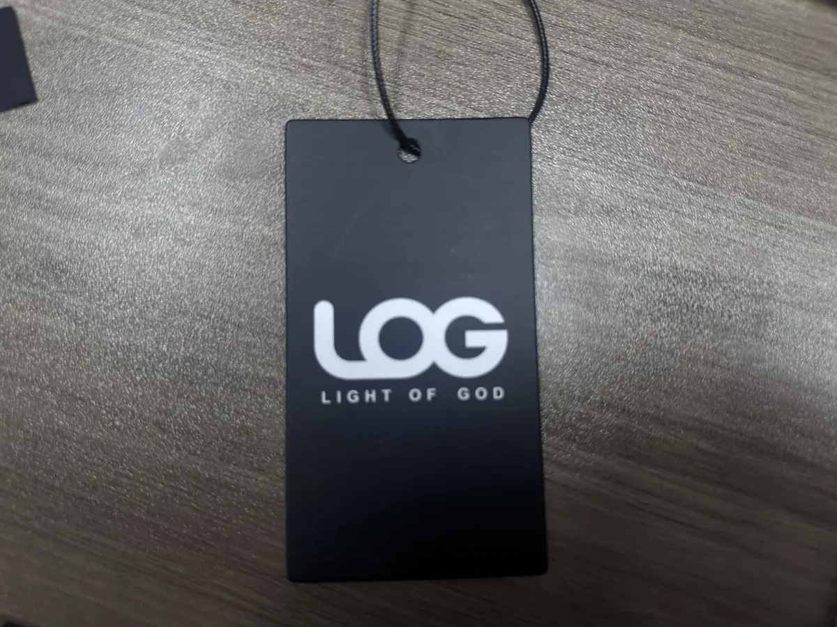 Black clothing hang tag with white logo, lettering and attached cord