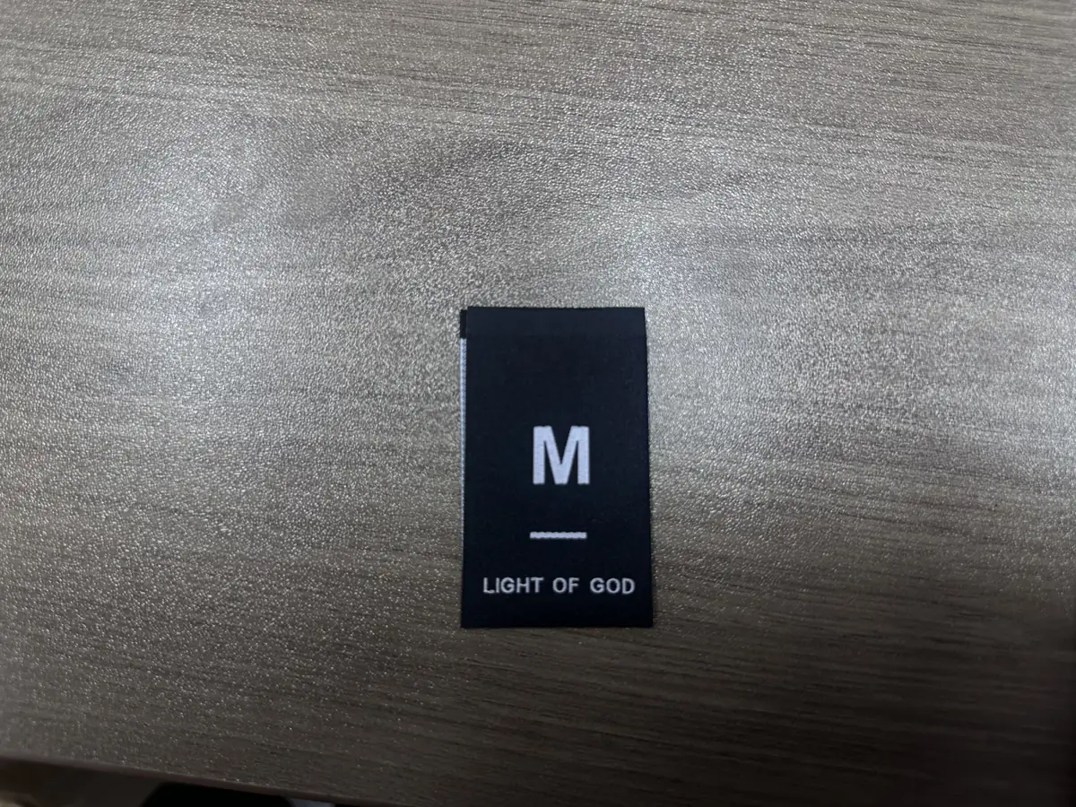 Black clothing size label showing M with white brand lettering